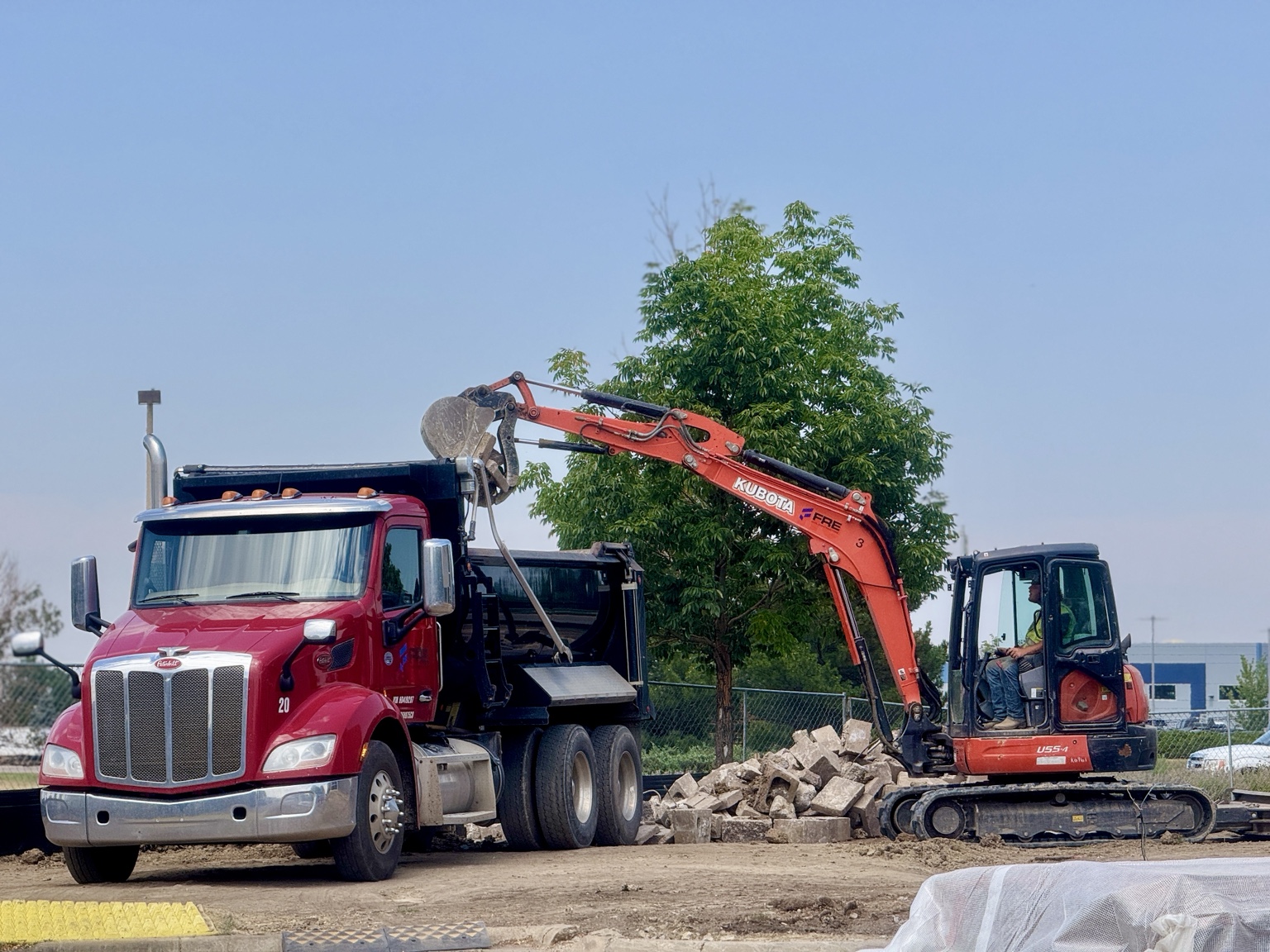 Kubota excavator loading a red Peterbilt dump truck
