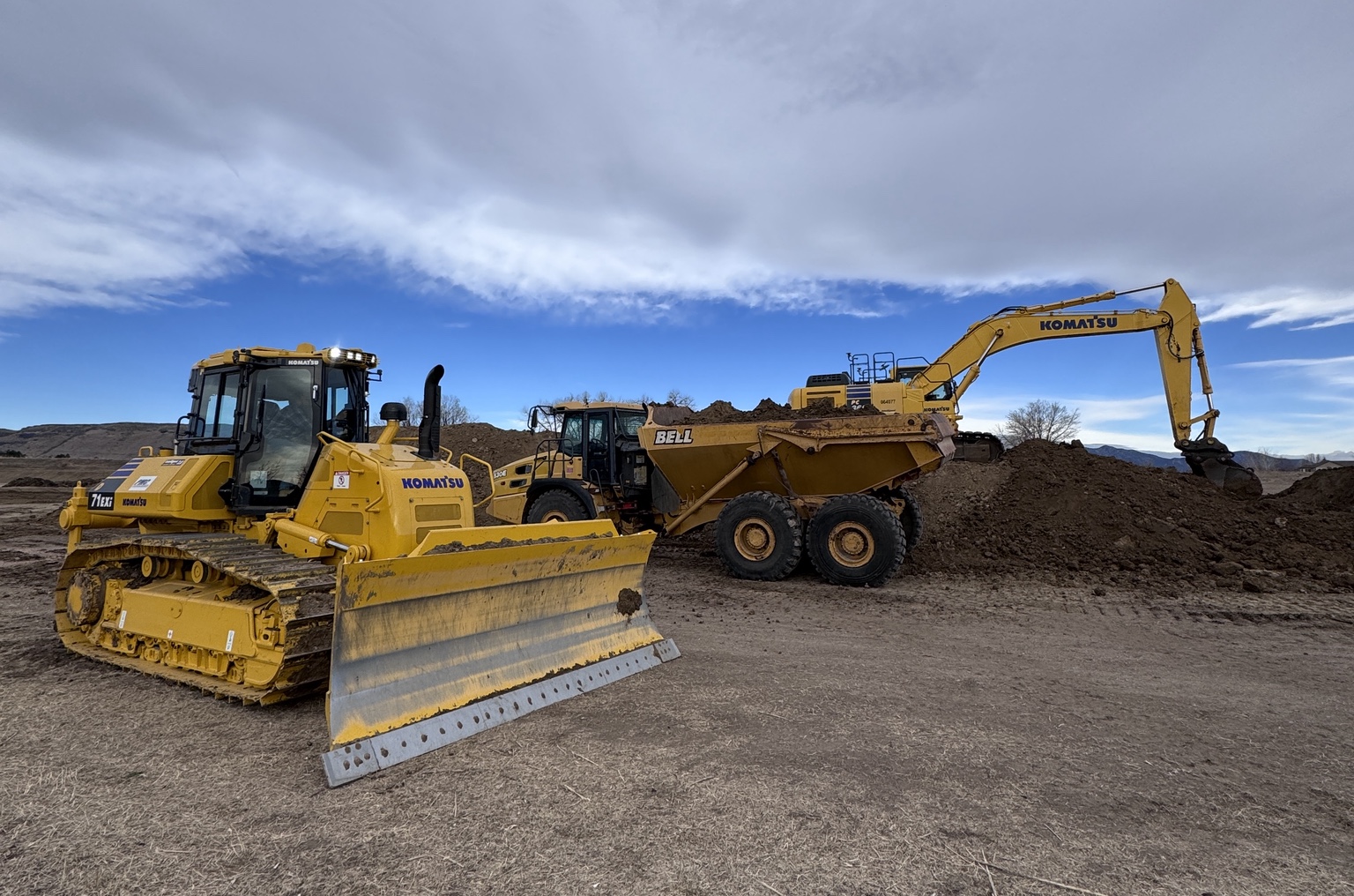 Komatsu dozer, articulated haul truck, and excavator on site